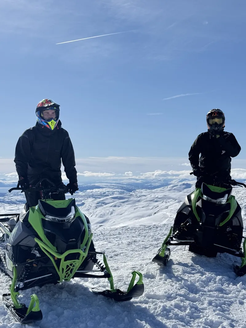 Två förare med Arctic Cat-skotrar på fjället