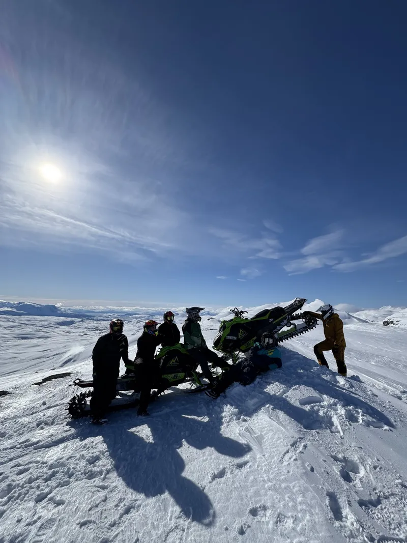 Skotergäng på fjälltoppen i solsken