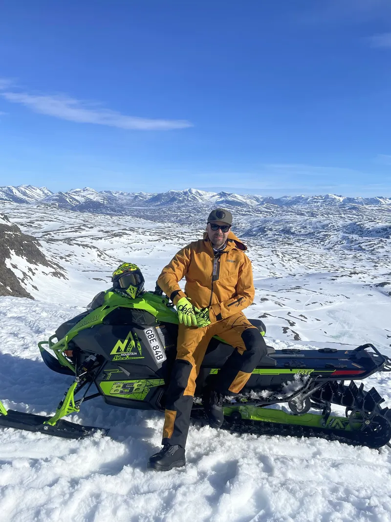 Förare vilar på sin Arctic Cat-skoter med fjällutsikt
