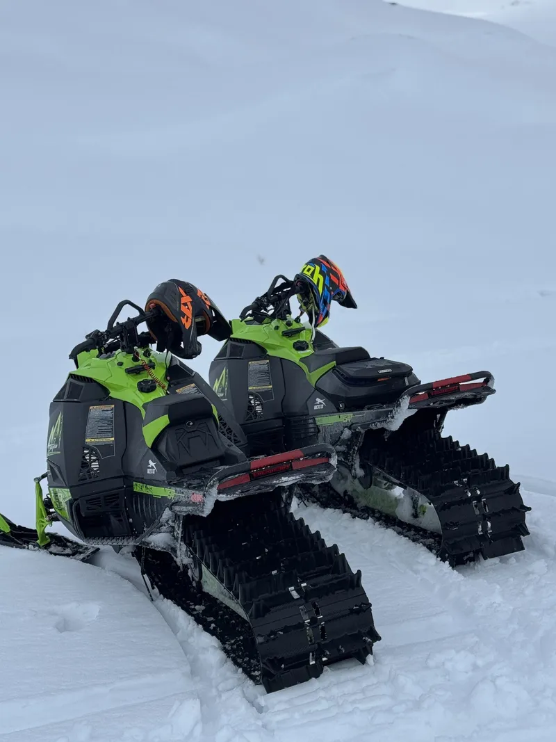 Två skotrar parkerade i djup snö